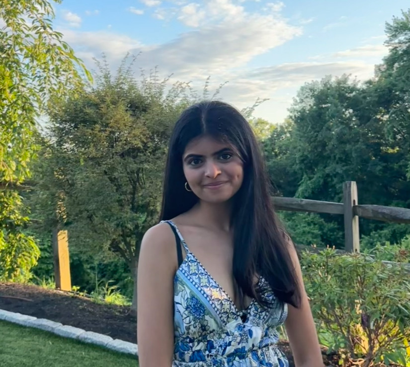 Niyati Dave standing outdoors by trees and a fence