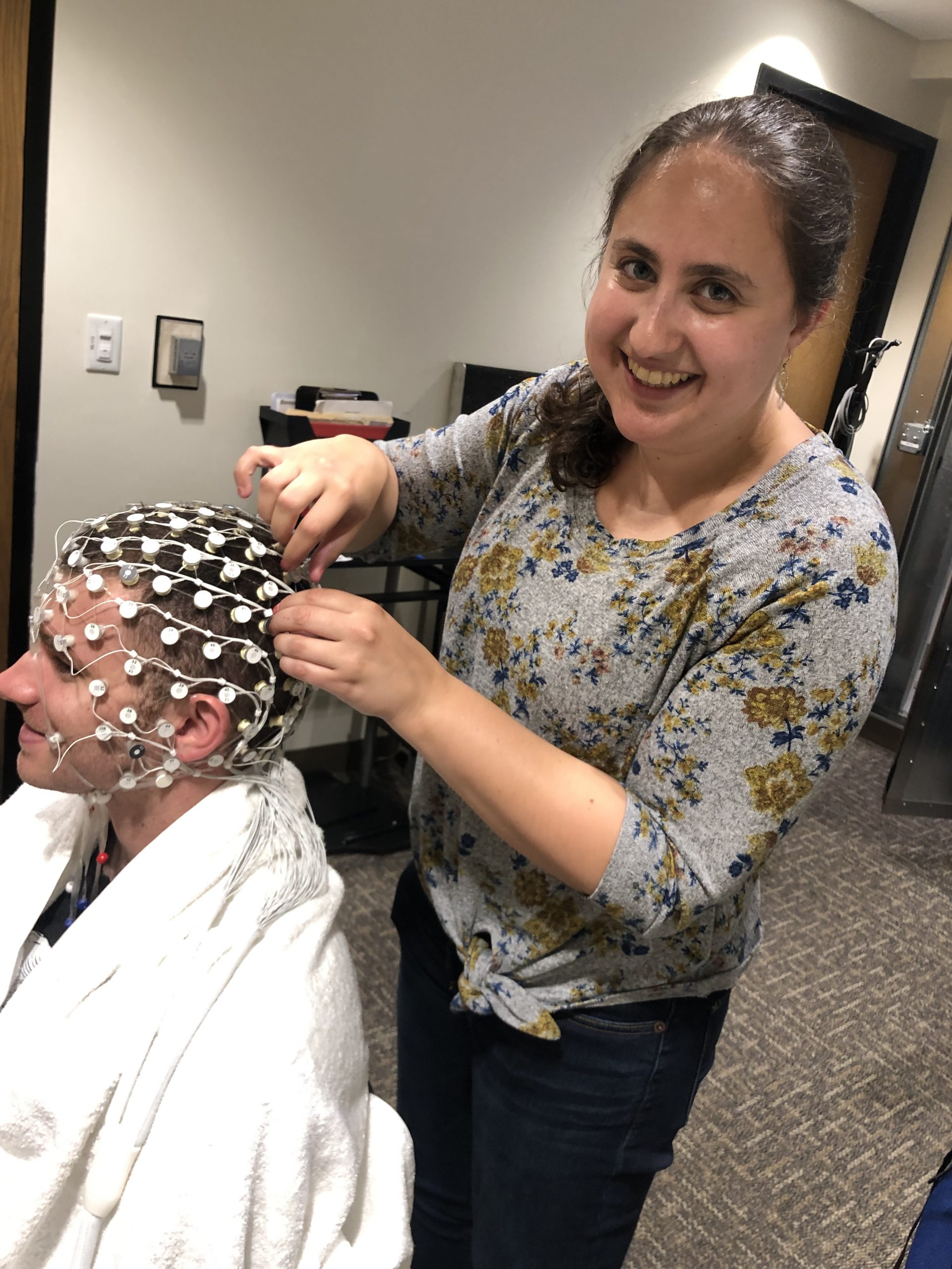 Arielle Keller placing an EEG electrode cap on a participant in a research lab