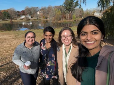 Arielle Keller, Hamsi Radhakrishnan, Heather Robinson, and Niyati Dave standing outside by a pond and smiling